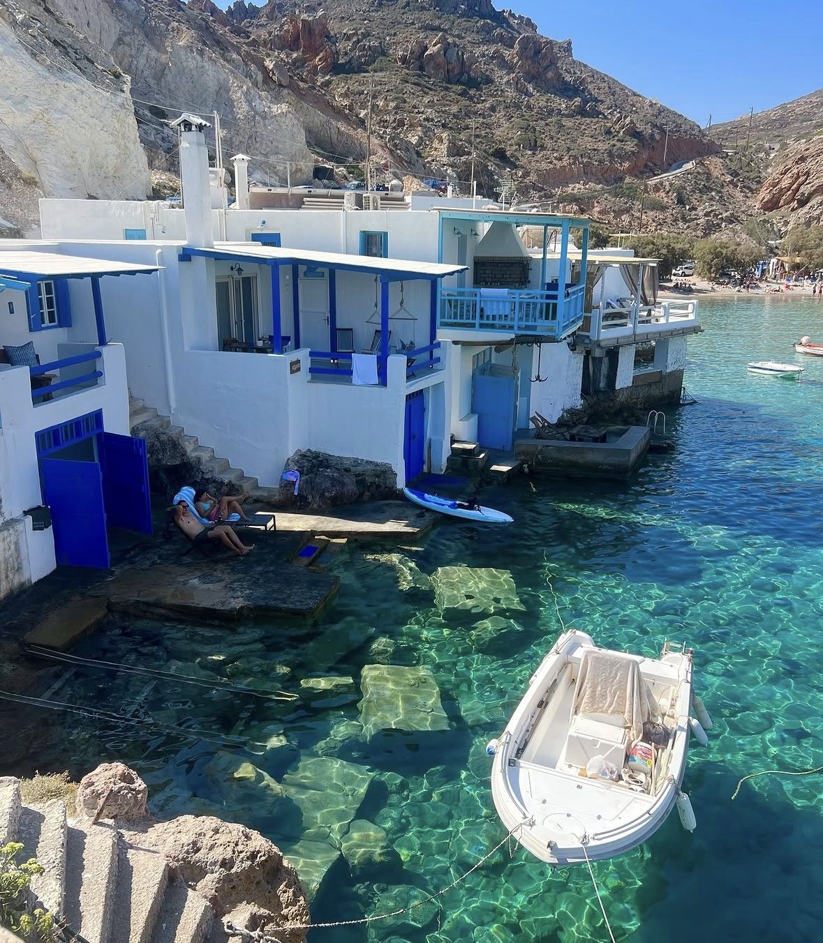 Snorkelling gear and beach bag laid out on the white volcanic rocks of a Milos beach